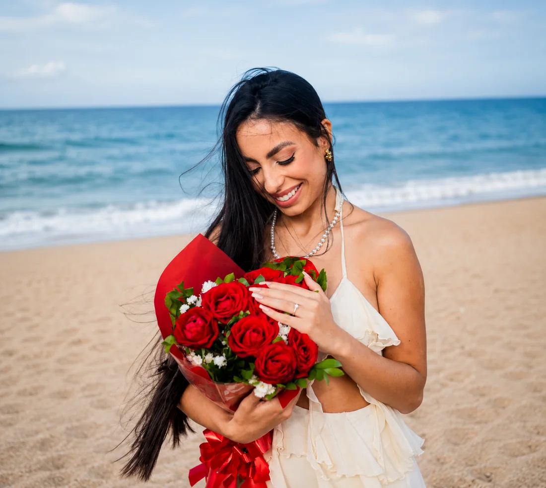 Mulher segurando um buquê de rosas na praia